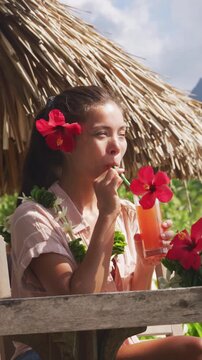 Breakfast at luxury on beach. Woman drinking fruit juice on summer vacation travel in Bora Bora island, Tahiti French Polynesia. Raw vertical video of real unretouched woman model without any makeup