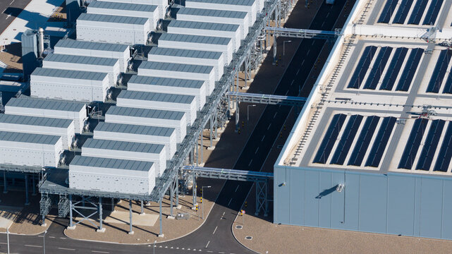 Aerial view of a modern industrial facility featuring rows of white technical units, complex piping, and a large building with solar panels on the roof in Groningen, Groningen, Netherlands.