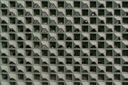 Seamless style full frame texture of a modern olive green breeze block wall featuring uniform geometric roster pattern for ventilation and light filtering.