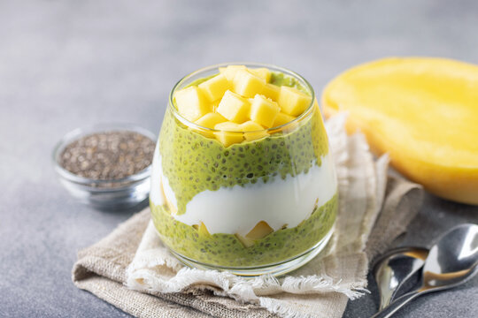 Chia pudding on coconut milk with matcha tea, mango slices and yoghurt in a glass. Healthy eating