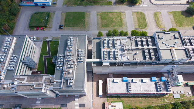 Aerial view of a modern data center facility featuring extensive rooftop cooling systems, industrial architecture, and surrounding paved parking areas in Settimo Milanese, Lombardy, Italy.