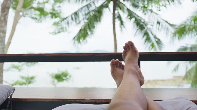 First-person view of someone relaxing with their feet propped up on a balcony, enjoying the serene ocean scenery during a tropical island getaway.