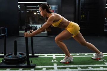 Woman pushing weighted sled in gym training session © milanmarkovic78