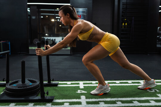 Woman pushing weighted sled in gym training session