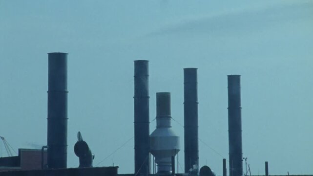 Industrial smokestacks emitting smoke from manufacturing plant factory facility.