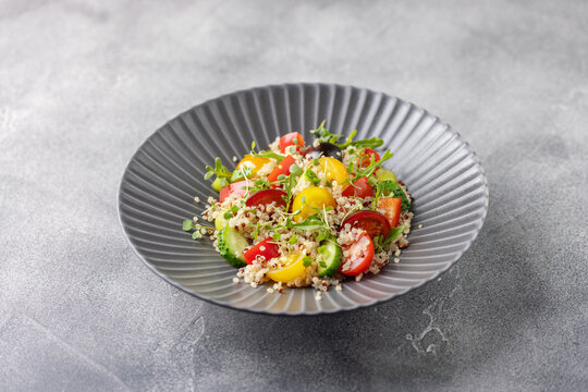 Quinoa salad with tomatoes, cucumber and red sweet pepper  in a ceramic bowl