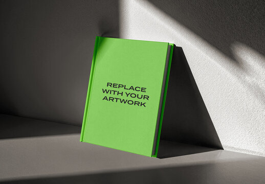 Hardcover book mockup standing upright on a textured surface with dramatic lighting, realistic cover presentation for graphic design, print media, and editorial content, template