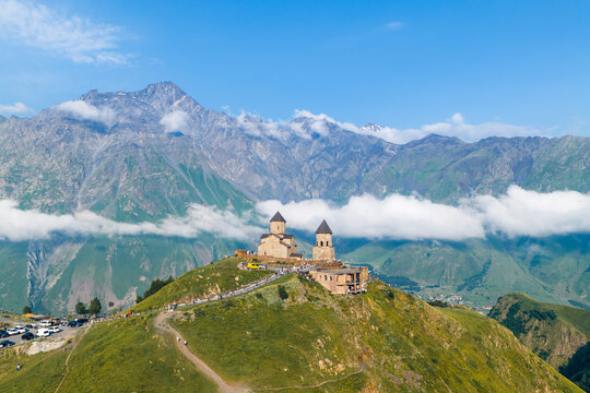 Aerial view of Gergeti Trinity Church on a grassy hilltop with the Caucasus Mountains in the background Oni, Mtskheta-Mtianeti, Georgia.