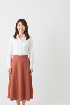 Young woman smiling in white blouse and coral skirt standing indoors