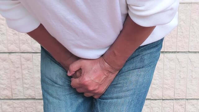 Old Southeast Asian man hand holding groin, concept of UTI urinary tract infection or bladder infection, fertility, prostate cancer disease, bladder medical sickness, front view
