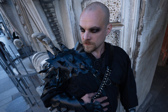 Bald man in a spiked leather pauldron and dark makeup, mens alternative style portrait