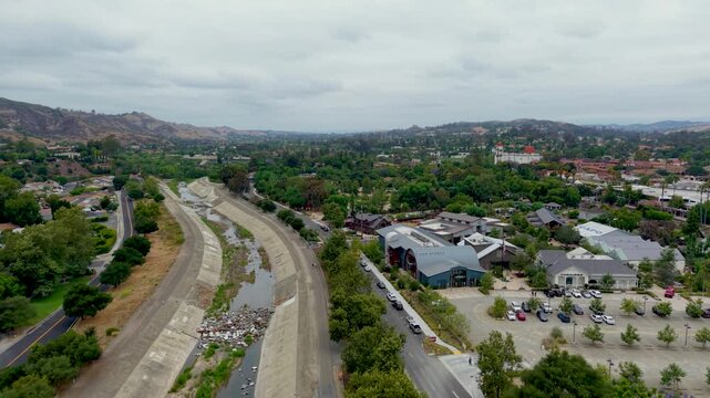Aerial view over San Juan Capistrano river channel and surrounding cityscape during a cloudy afternoon.
