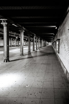 Hanover, Germany - July 1, 2026: Black and white view along a covered railway platform passage with repeating cast-iron columns at Hannover Hauptbahnhof.