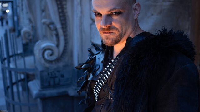 Male portrait with smoky eye makeup, fur collar and leather pauldron, men beauty and style.