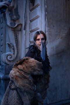 Fur coat and black leather cape on a model in a chain mask, luxury winter outerwear