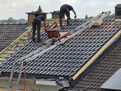 Ouvriers qui r&eacute;novent la toiture d&rsquo;une maison pour isolation et remplacement des tuiles