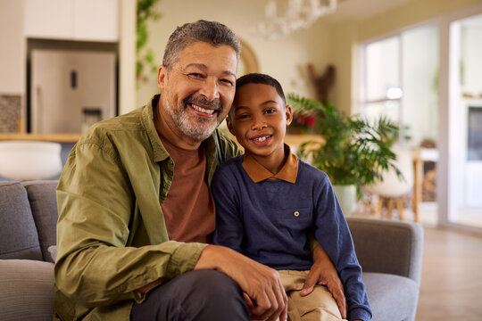 Portrait of happy smiling child embracing grandfather while looking at camera