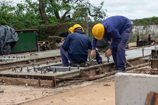 Construction workers working on precast concrete formwork and steel anchor bolts
