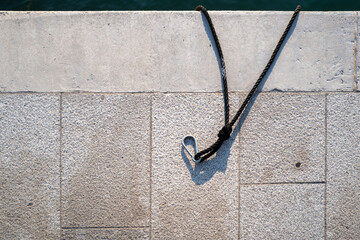 Naklejka premium Rope moored to concrete pier under bright sun