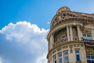 Ornate historic building facade in Belgrade with sculpted columns, curved balconies, decorative reliefs, windows, and blue sky with clouds © Mila