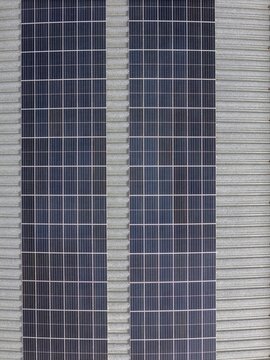 Aerial view of solar panels installed on a corrugated metal roof in Coimbra, Coimbra, Portugal.