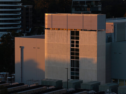 Aerial view of a modern data center building illuminated by golden hour sunlight with cooling units on the roof in Sydney, New South Wales, Australia.