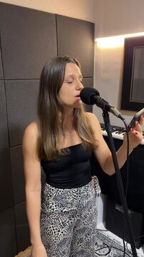 Mulher canta com microfone em est&uacute;dio 
