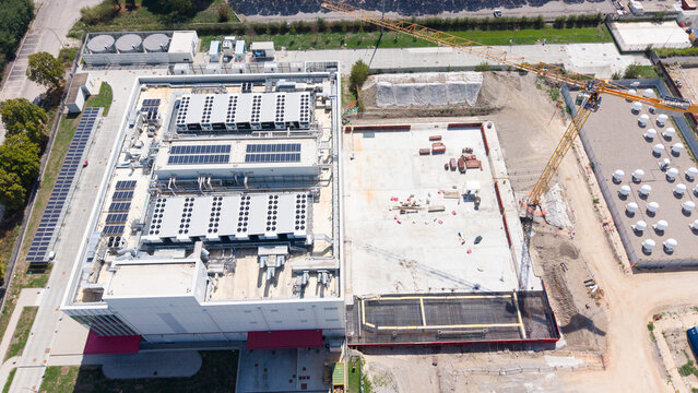 Aerial view of the Equinix ML5 data center featuring rooftop HVAC units and solar panels, adjacent to a construction site with a tower crane in Castelletto, Lombardia, Italy.