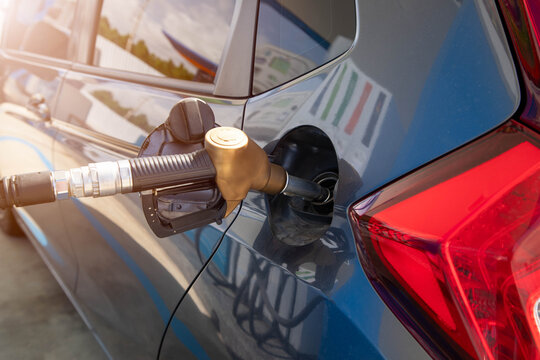 Refueling a modern car at petrol station, fuel pump nozzle inside fuel tank cap, concept of rising gasoline prices