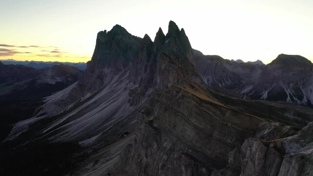 Stunning cinematic aerial view of Seceda mountain range in Italian Dolomites during early morning sunrise.