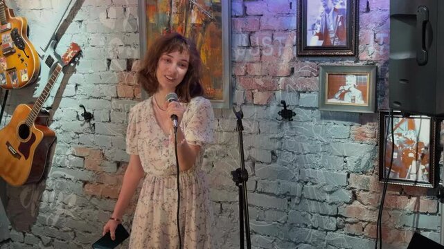 Emotional Young Female Stand Up Comedian Telling Jokes Into Microphone On Stage In Cozy Brick Wall Club Interior With Guitars Handheld Live Audience POV Authentic Entertainment Performance Medium Shot