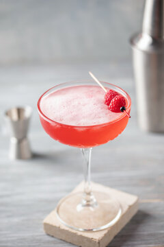 Alcoholic cocktail clover club with raspberries in a cocktail glass on the table.