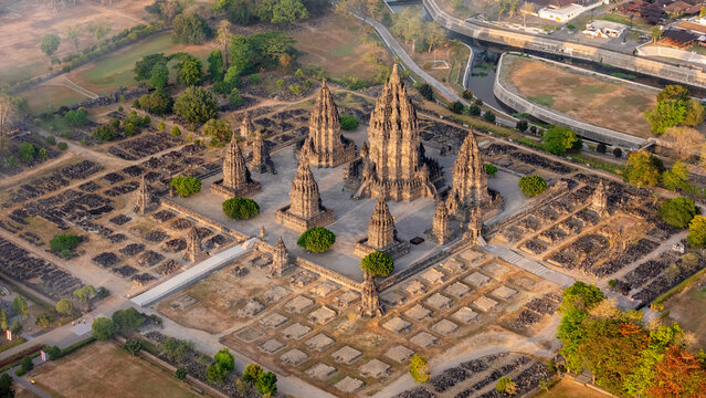 Aerial view of the historic Prambanan Temple complex with its iconic tall stone spires, surrounding ruins, and lush greenery in Kecamatan Prambanan, Daerah Istimewa Yogya, Indonesia.