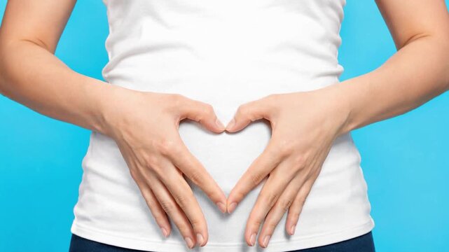 Woman Making Heart Shape with Hands on Stomach on Blue Background for Gut Health and Probiotics Concept