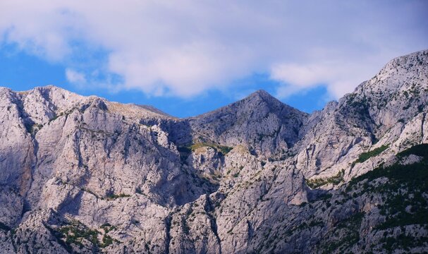 Big mountain peak scene with sun light and white clouds on a blue sky, mountain landscape background