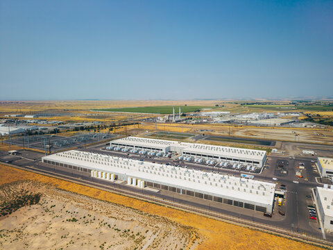 Aerial view of a data center facility with large industrial buildings, cooling units, and surrounding arid landscape in Umatilla, Oregon, United States.