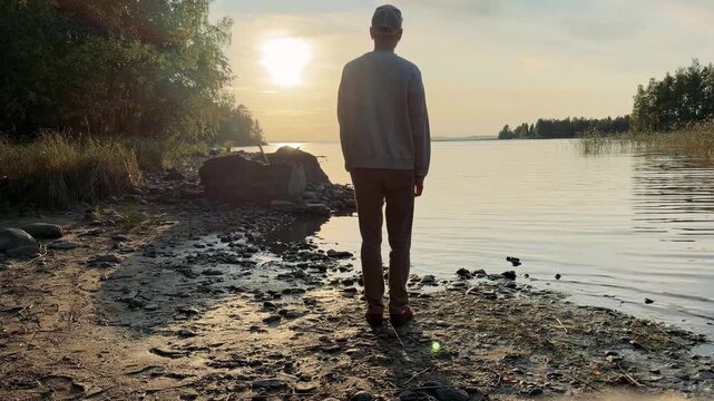 Man Spreading His Arms at a Lake Shore in the Evening Sun