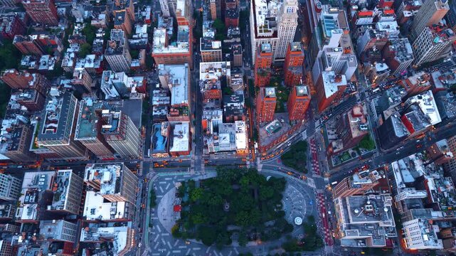 Little green park surrounded by dense urban landscape. Flying high over the rooftops of modern New York City, USA.