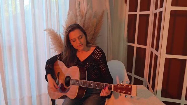 Mulher tocando viol&atilde;o acustico em casa 