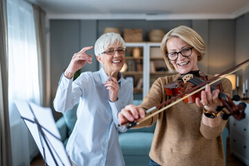 Senior women enjoying music lesson and friendship at home © Migma_Agency