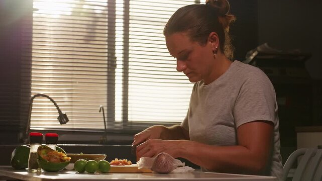 Woman Chops Ingredients for Fresh Guacamole at a Kitchen Counter, Supporting Healthy Eating and Food Preparation