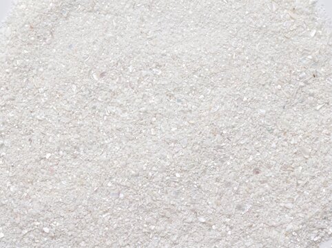 A close-up, overhead view of a pile of fine white sugar crystals, sparkling under light.