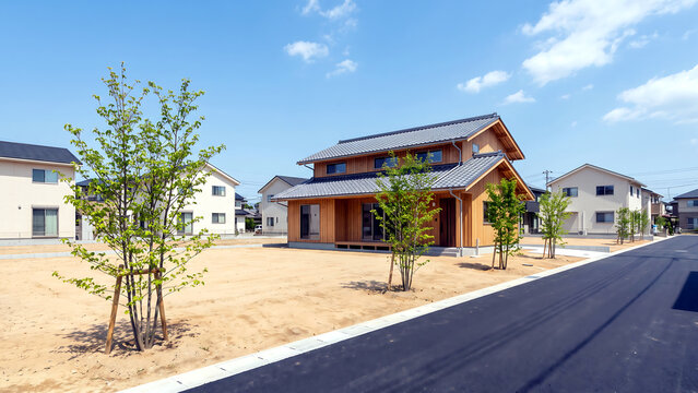 青空の下の分譲地に建つ二階建ての新築住宅と整えられた区画