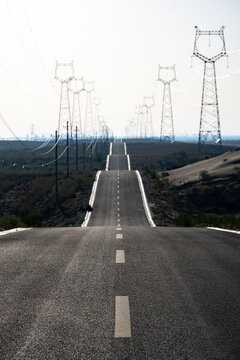 High voltage transmission towers extending along the desert highway road