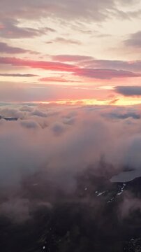 Aerial view above the clouds at sunrise over Iceland&rsquo;s Highlands as colorful morning light illuminates dramatic cloud layers revealing glimpses of volcanic terrain below