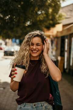 Happy woman laughing enjoying coffee walking street