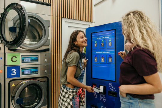 Young women friends paying for laundry services