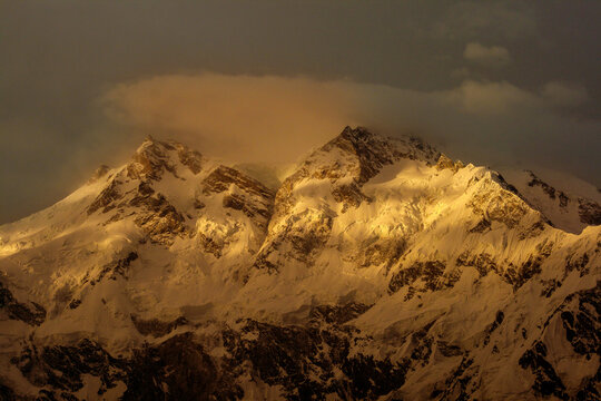 View of Nanga Parbat with snow-covered peaks illuminated by golden hour light in Pakistan.