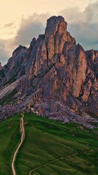 Smooth drone flight around the dramatic rock formations of Passo Giau in the Dolomites. Golden evening light reveals rugged alpine scenery, mountain trails and breathtaking landscapes.