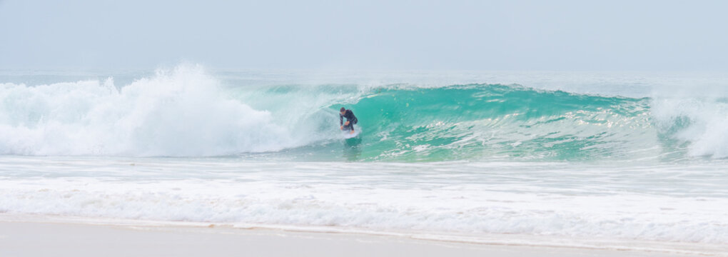 young adult surfing on a big wave in the ocean